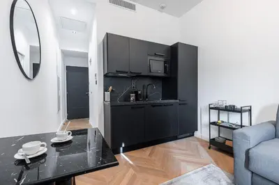 a kitchen with black cabinets and a table in a room at 7 FOCH 202 - Studio contemporain en plein coeur de Nice - climatisation in Nice