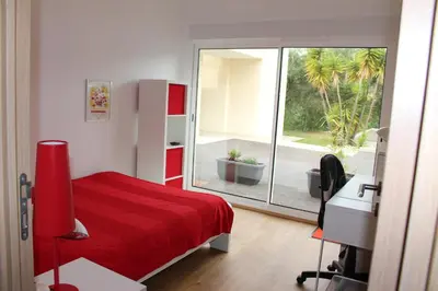 a bedroom with a red bed and a desk and a window at Petite maison, cosy, sur les collines niçoises in Nice