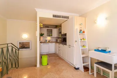 a small kitchen with white cabinets and a staircase at LA CASA AP4409 By Riviera Holiday Homes in Villefranche-sur-Mer