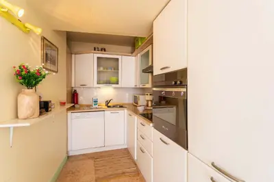 a white kitchen with white cabinets and a vase of flowers at LA CASA AP4409 By Riviera Holiday Homes in Villefranche-sur-Mer