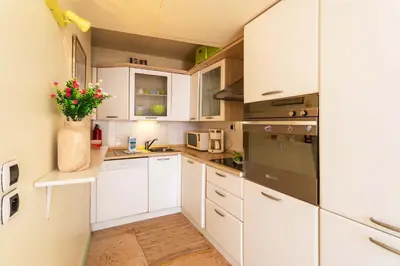 a kitchen with white cabinets and a vase of flowers at LA CASA AP4409 By Riviera Holiday Homes in Villefranche-sur-Mer
