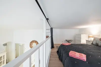 a bedroom with a bed in a white room at La Petite Chaise Bleue Appartement classe 3 etoiles in Nice