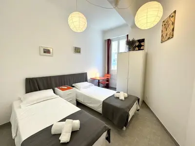 a bedroom with two beds and a table and lights at ApartHotel Riviera - MAISON DU GRAND SUD - Confortable petit 3 pièces - Promenade des Anglais in Nice