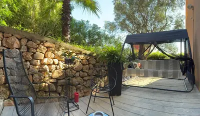 a patio with a stone wall and a table and chairs at Rez de jardin avec vue mer à saint jean in Saint-Jean-Cap-Ferrat