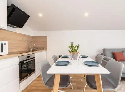 a white dining room table with chairs and a kitchen at Beau deux pièces cozy avec terrasse n11 in Nice