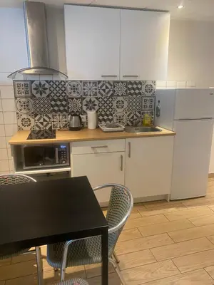 a kitchen with white cabinets and a table and chairs at Appartement Nice proche de Monaco in Nice