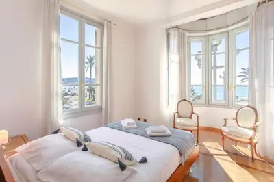 a bedroom with a bed with two chairs and windows at #15 Sea front Villa AC stunning view for 6 pers wifi in Nice