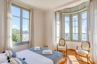 a bedroom with a bed and two chairs and windows at #15 Sea front Villa AC stunning view for 6 pers wifi in Nice