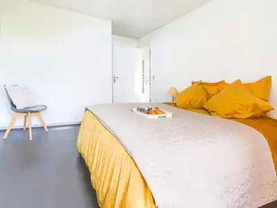 a bedroom with a large bed with yellow pillows and a chair at Apartment Les Balcons d'Eze-3 by Interhome in Èze