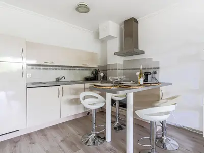 a kitchen with white cabinets and a island with stools at Apartment Les Balcons d'Eze-3 by Interhome in Èze