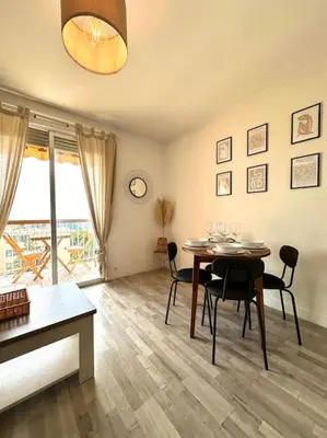 a dining room with a table with chairs and a television at Joli 2 pièces - Proche aéroport - Terrasse vue mer in Nice