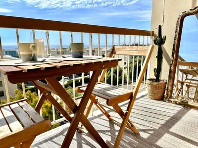 a table on a balcony with a coffee cup on it at Joli 2 pièces - Proche aéroport - Terrasse vue mer in Nice