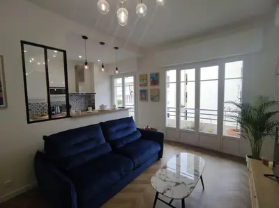 a living room with a blue couch and a glass table at Bel appartement - plage à 50 m in Nice