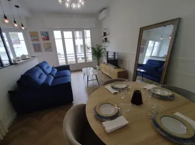 a living room with a table and a blue couch at Bel appartement - plage à 50 m in Nice