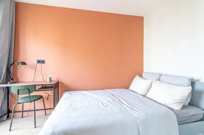 a bedroom with an orange wall and a bed and a desk at Charmant appartement à Nice in Nice