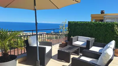 a patio with chairs and an umbrella and the ocean at Chambre d'hôtes pleine vue mer in Nice