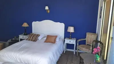 a blue bedroom with a white bed and two chairs at Chambre d'hôtes pleine vue mer in Nice