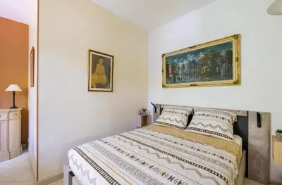 a bedroom with a bed with a painting on the wall at Studio charmant à Cagnes-sur-Mer de 35 m² + piscine privée in Cagnes-sur-Mer
