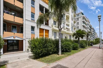 an apartment building with palm trees and a sidewalk at Loft Le Galet FSHH in Nice