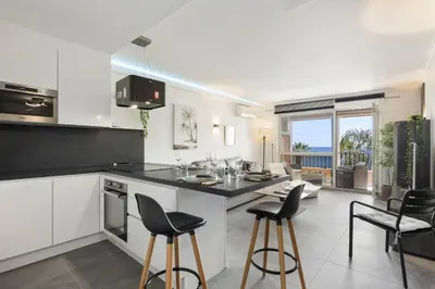 a kitchen with white cabinets and black counter tops at Loft Le Galet FSHH in Nice