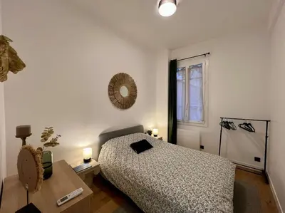 a bedroom with a bed and a table and a window at Les Orangers - 3 Pièces avec terrasse arborée in Nice