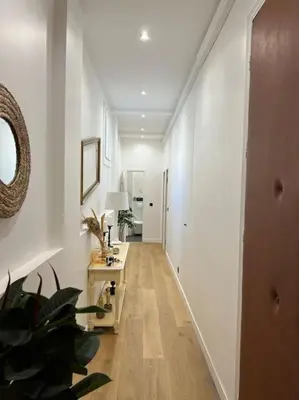 a hallway with white walls and a table with a lamp at Les Orangers - 3 Pièces avec terrasse arborée in Nice