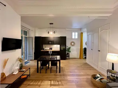 a living room with a table and a kitchen at Les Orangers - 3 Pièces avec terrasse arborée in Nice