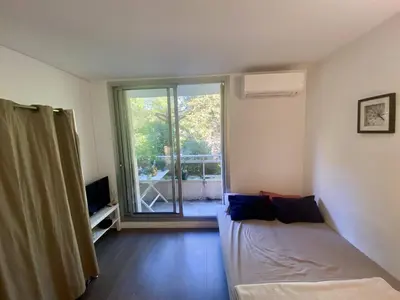 a living room with a bed and a sliding glass door at Nice ouest-Cosy Studio, Clim Wifi in Nice