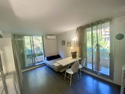 a living room with a table and a bed and windows at Nice ouest-Cosy Studio, Clim Wifi in Nice