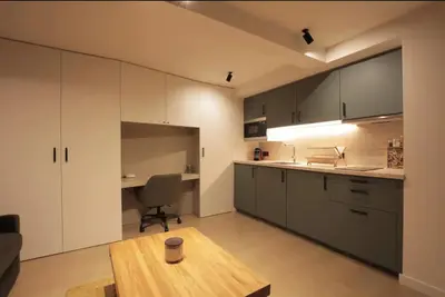 a kitchen with white cabinets and a wooden table at Fully equiped newly refurbished studio with an incredible view in Nice in Nice