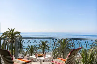 a table and chairs on a balcony overlooking the ocean at Suite Grand Sud FSHH in Nice
