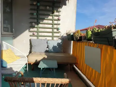a patio with a couch and a chair on a balcony at Bel appartement lumineux T3 Terrasse in Nice