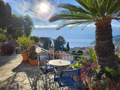 a table and chairs on a balcony with a palm tree at Villa Bethanie in Villefranche-sur-Mer
