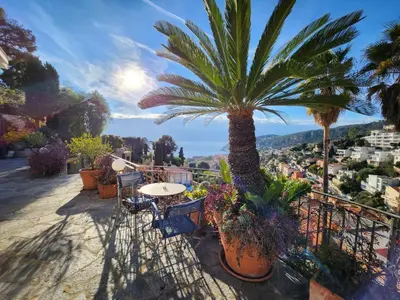a palm tree on a balcony with a table and chairs at Villa Bethanie in Villefranche-sur-Mer