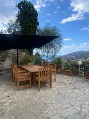 a wooden table and chairs under a black umbrella at Villa Bethanie in Villefranche-sur-Mer