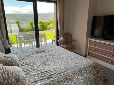 a bedroom with a bed and a television and a balcony at Joli 3 pièces ensoleillé sur les hauteurs de Nice in Nice