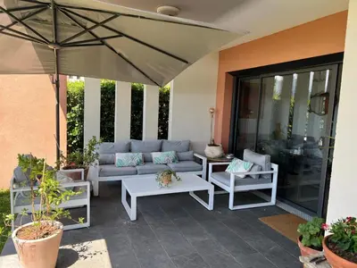 a patio with a couch and tables and an umbrella at Joli 3 pièces ensoleillé sur les hauteurs de Nice in Nice