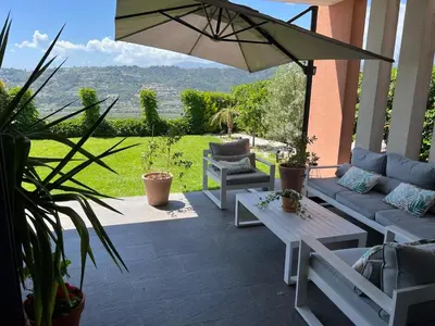 a patio with couches and a table and an umbrella at Joli 3 pièces ensoleillé sur les hauteurs de Nice in Nice