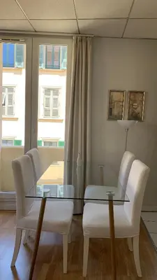 a dining room with a glass table and white chairs at 1 bedroom flat in the best street Nice in Nice
