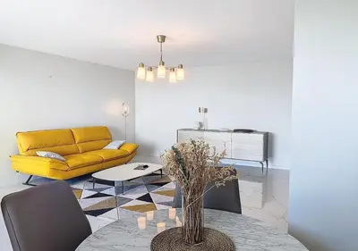 a living room with a yellow couch and a table at Horizon bleu vue mer dernier étage clim in Saint-Laurent-du-Var