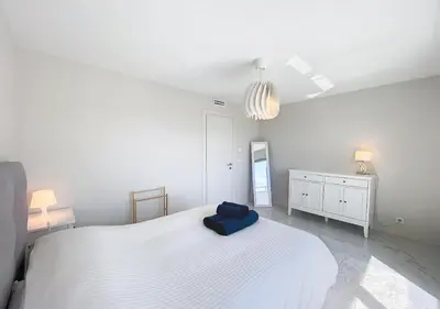 a bedroom with a large white bed with a blue pillow on it at Horizon bleu vue mer dernier étage clim in Saint-Laurent-du-Var