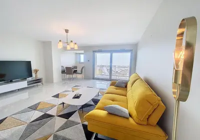 a living room with a yellow couch and a tv at Horizon bleu vue mer dernier étage clim in Saint-Laurent-du-Var