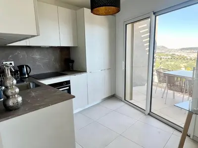 a kitchen with white cabinets and a view of a patio at Panoramic Sea View Appartment Blue Pearl in Nice