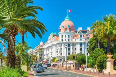 a building with a dome on a street with palm trees at Appartement Nice Libération in Nice