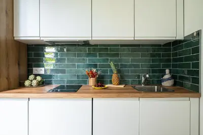 a kitchen with white cabinets and green subway tiles at Pink Palace - Quartier Authentique Libération in Nice