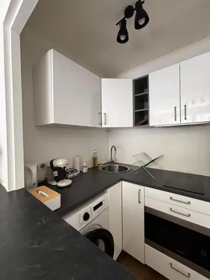 a kitchen with white cabinets and a black counter top at Nice appartement for 2 adults with air-conditioning in Nice