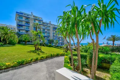a building with palm trees in front of a park at Port de Nice, Charmant studio in Nice