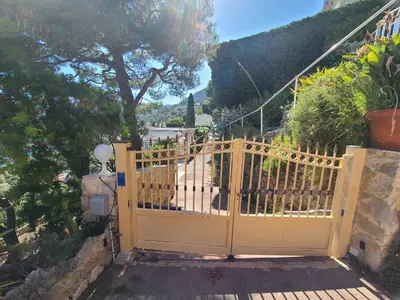 an open yellow gate with a view of a street at Eze sur mer - vue Saint Jean Cap Ferrat in Èze