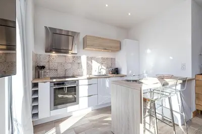 a kitchen with white cabinets and a counter top at 253 MONT BORON - Appartement 2p - Balcon plein sud - Climatisation in Nice