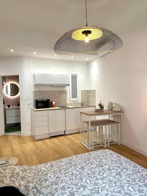 a kitchen with white cabinets and a table in a room at Studio Cosy à Nice Centre in Nice